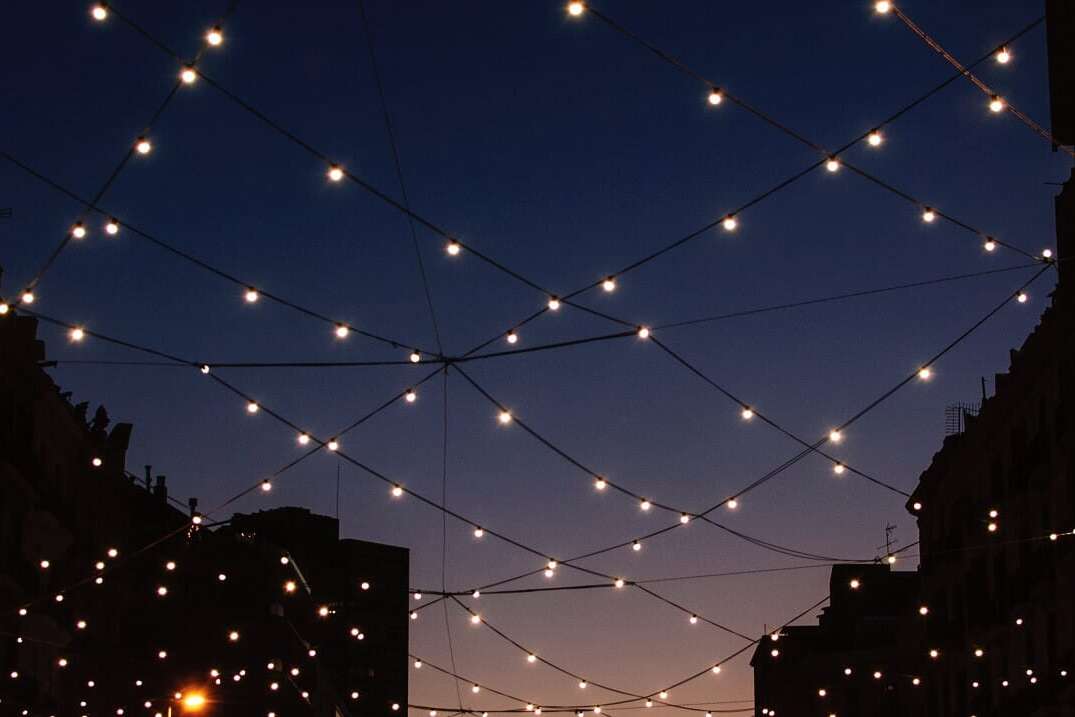 Photo of a street looking up to a night sky with fairy lights in a net formation, representing a blog titled 'Optimising network onboarding to an invoice platform'