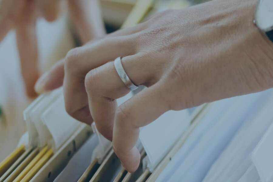 Close up stock image of business executive hands searching through paper business files. Representing blog post titled 'Transforming Business Tax reporting with technology'