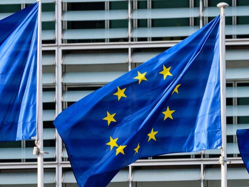 Photo of 3 EU flags flying outside a governmental building. Representing a blog titled 'ViDA: Everything you should know about VAT in the Digital Age'