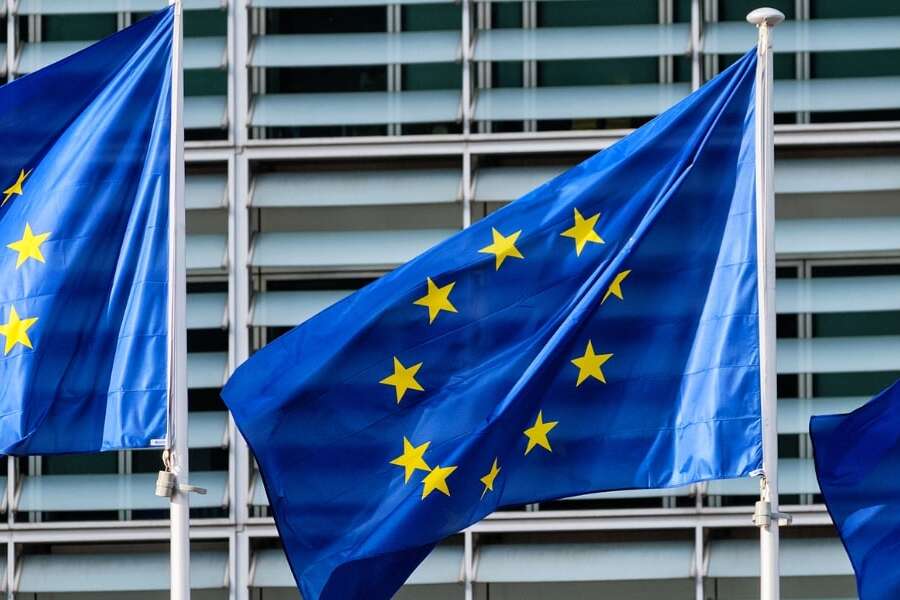 Photo of 3 EU flags flying outside a governmental building. Representing a blog titled 'ViDA: Everything you should know about VAT in the Digital Age'